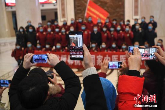 2月21日，長沙，眾人拿出手機拍攝出征的醫(yī)護人員。當日，由湖南省中醫(yī)藥管理局組建的第五批國家中醫(yī)醫(yī)療隊出征湖北，醫(yī)療隊共有成員35人，將增援武漢江夏方艙醫(yī)院。中新社記者 楊華峰 攝